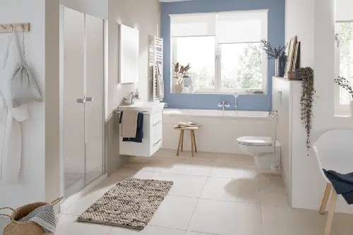 Helles Badezimmer mit Badewanne unter dem Fenster, Duschkabine, Hängeschrank und natürlicher Deko – concept 100 Serie im skandinavischen Stil.